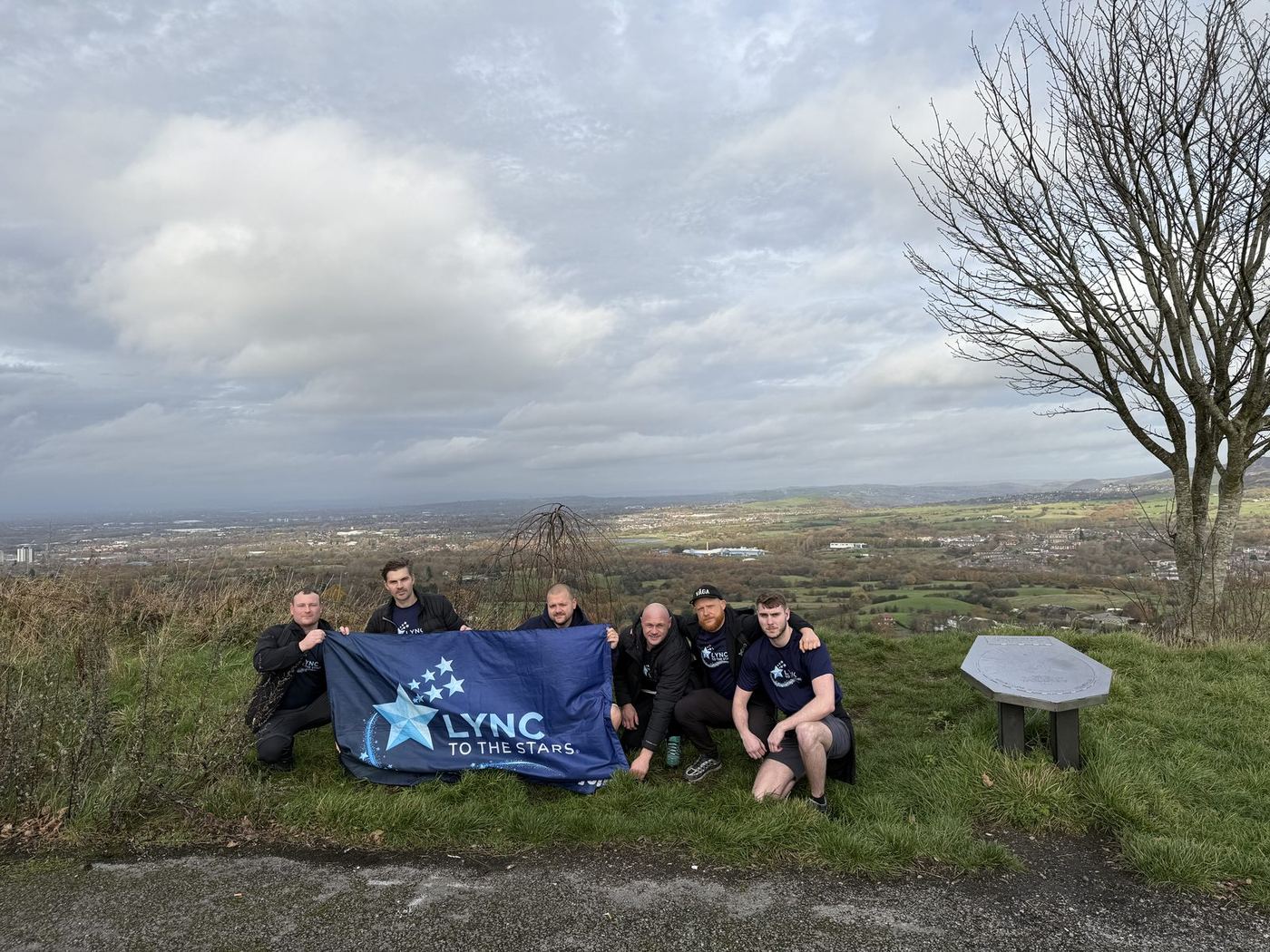 Friends holding the Lync to the Stars banner near the tree