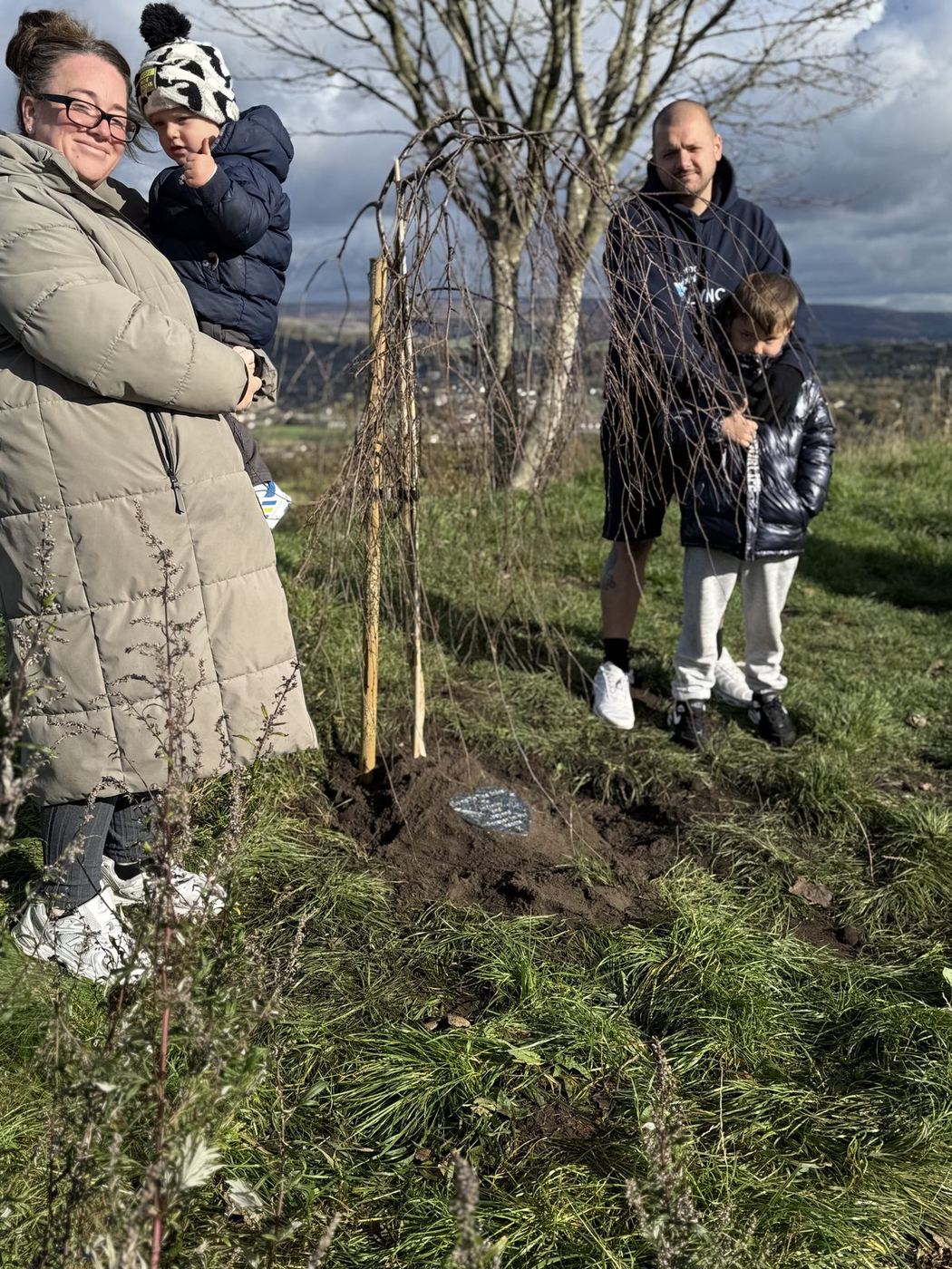 Family gathered around Lync's Tree on the hillside