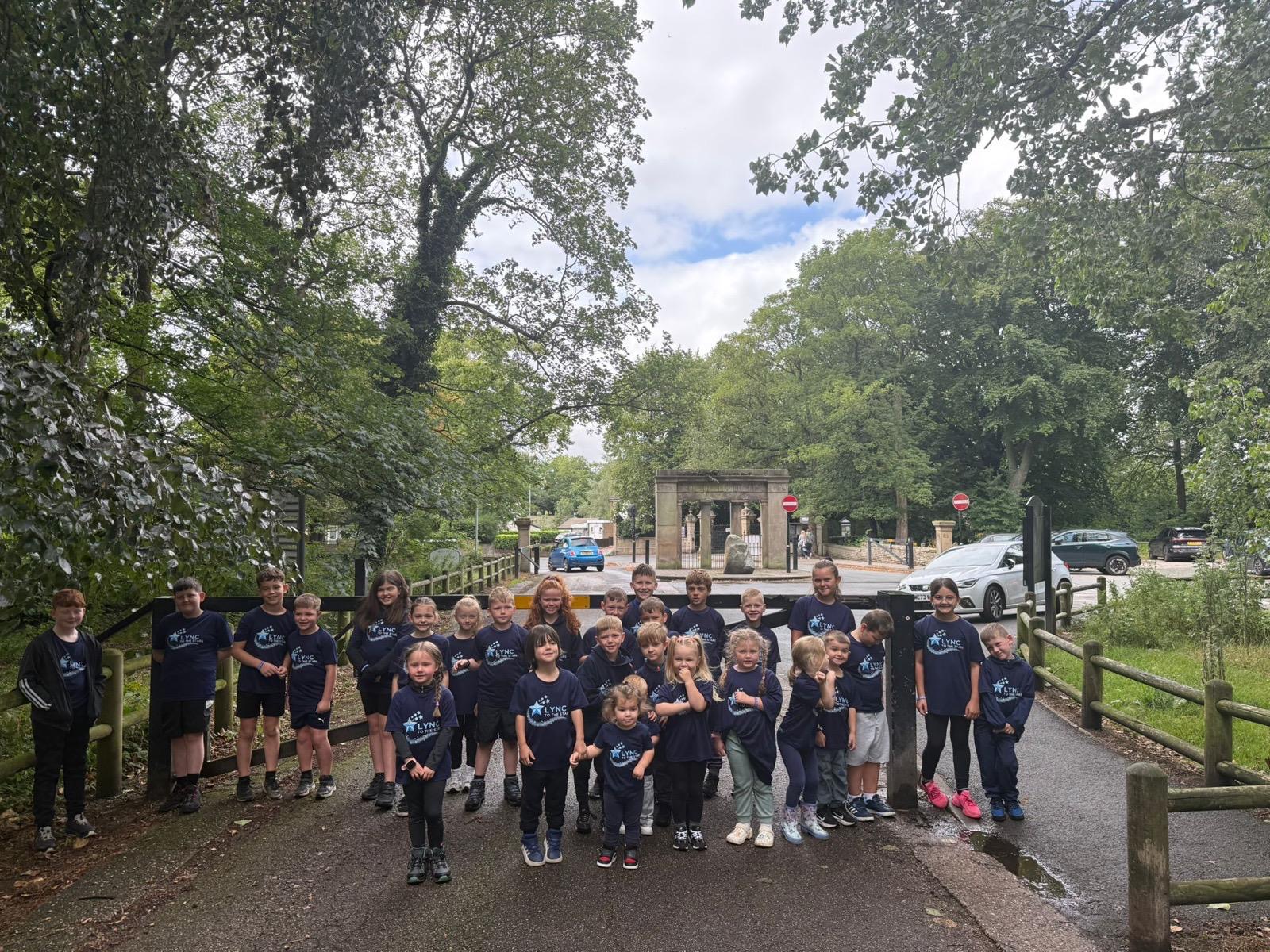 A big group of children in Lync shirts by the park entrance