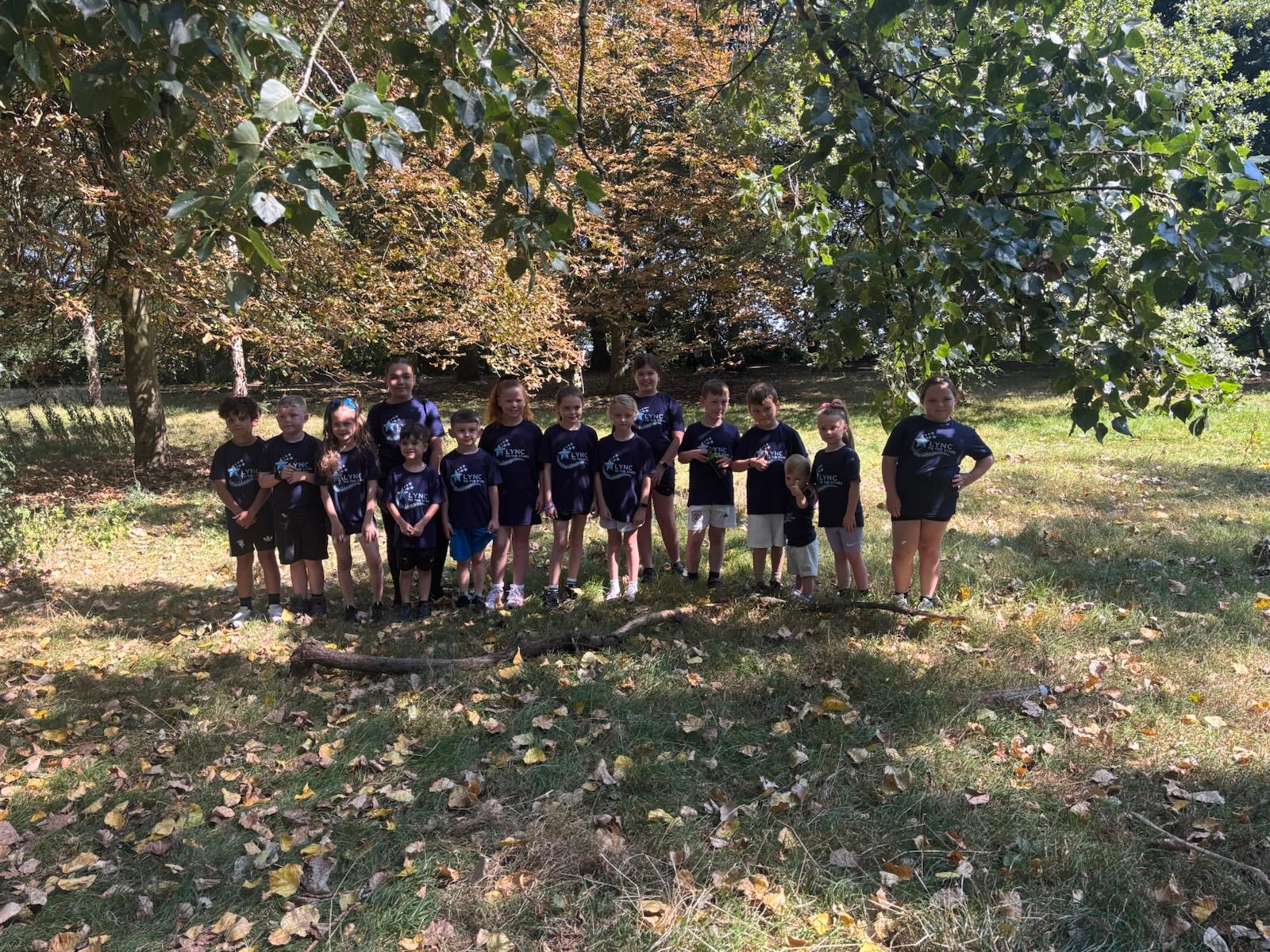 Children standing together under the trees in the summer sunshine