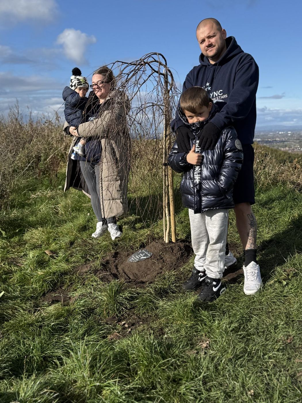 Family standing together beside Lync's Tree
