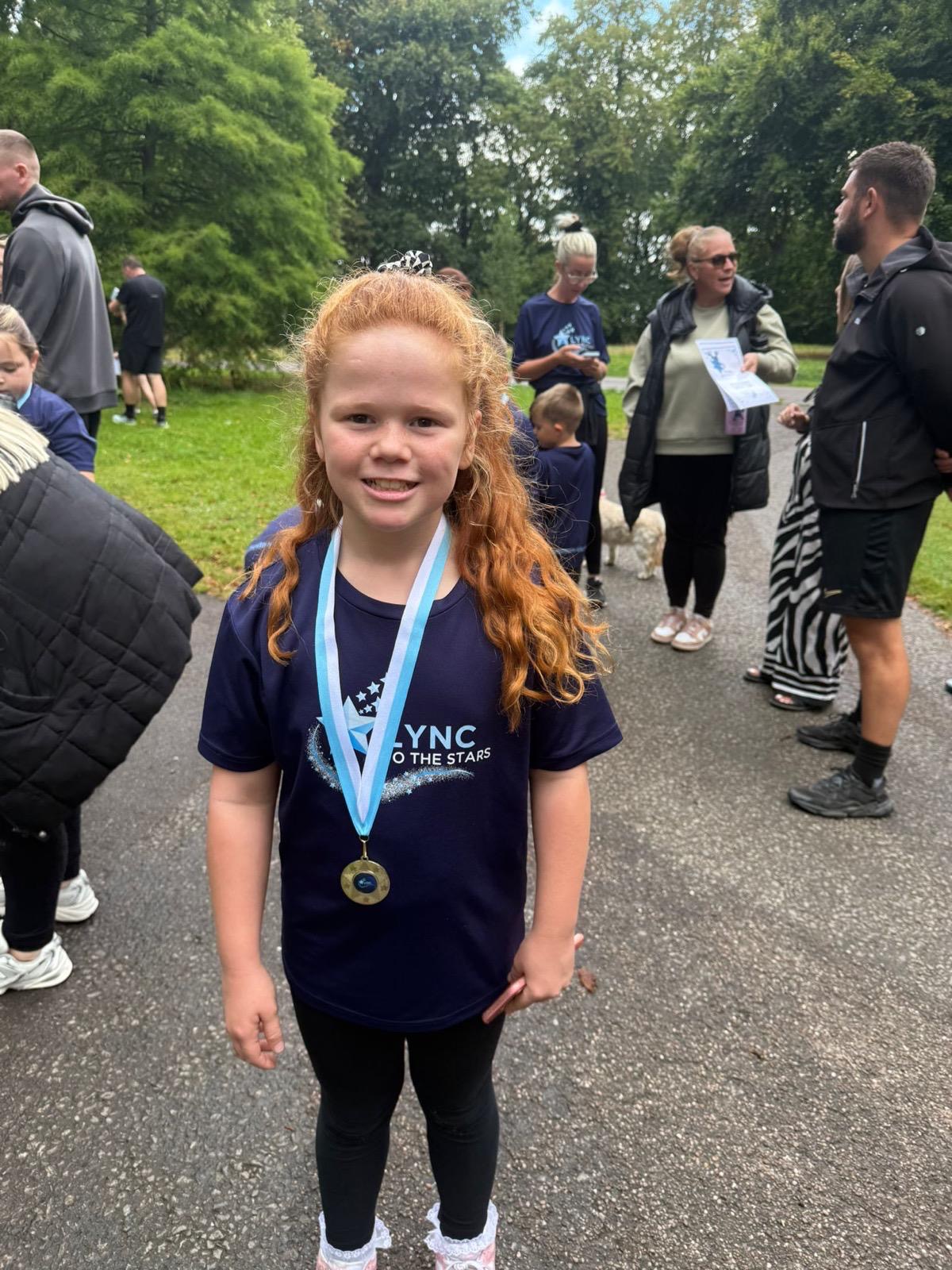 A proud young girl wearing her Lync shirt and medal