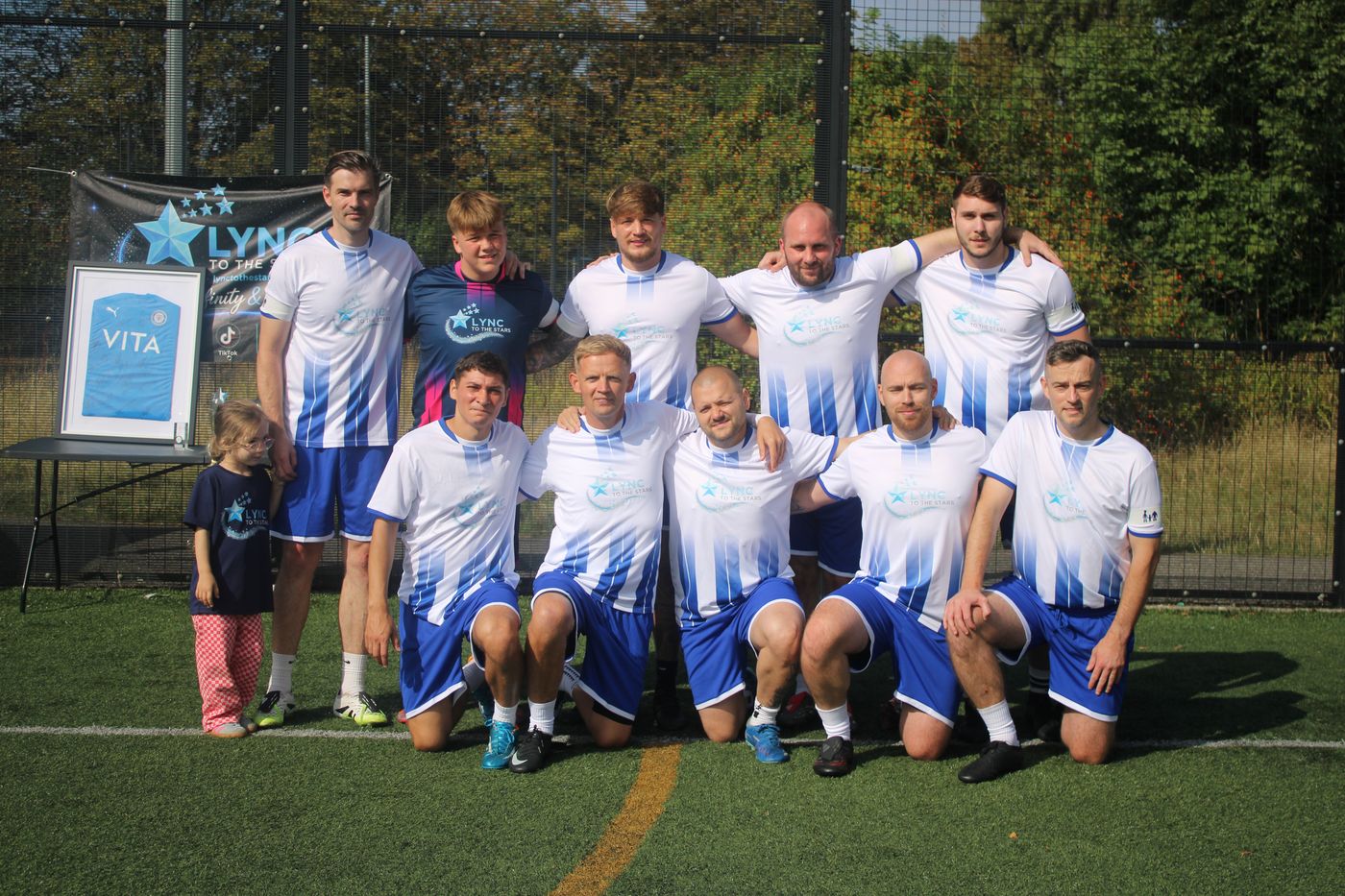 A team in blue and white kits with the framed shirt and banner
