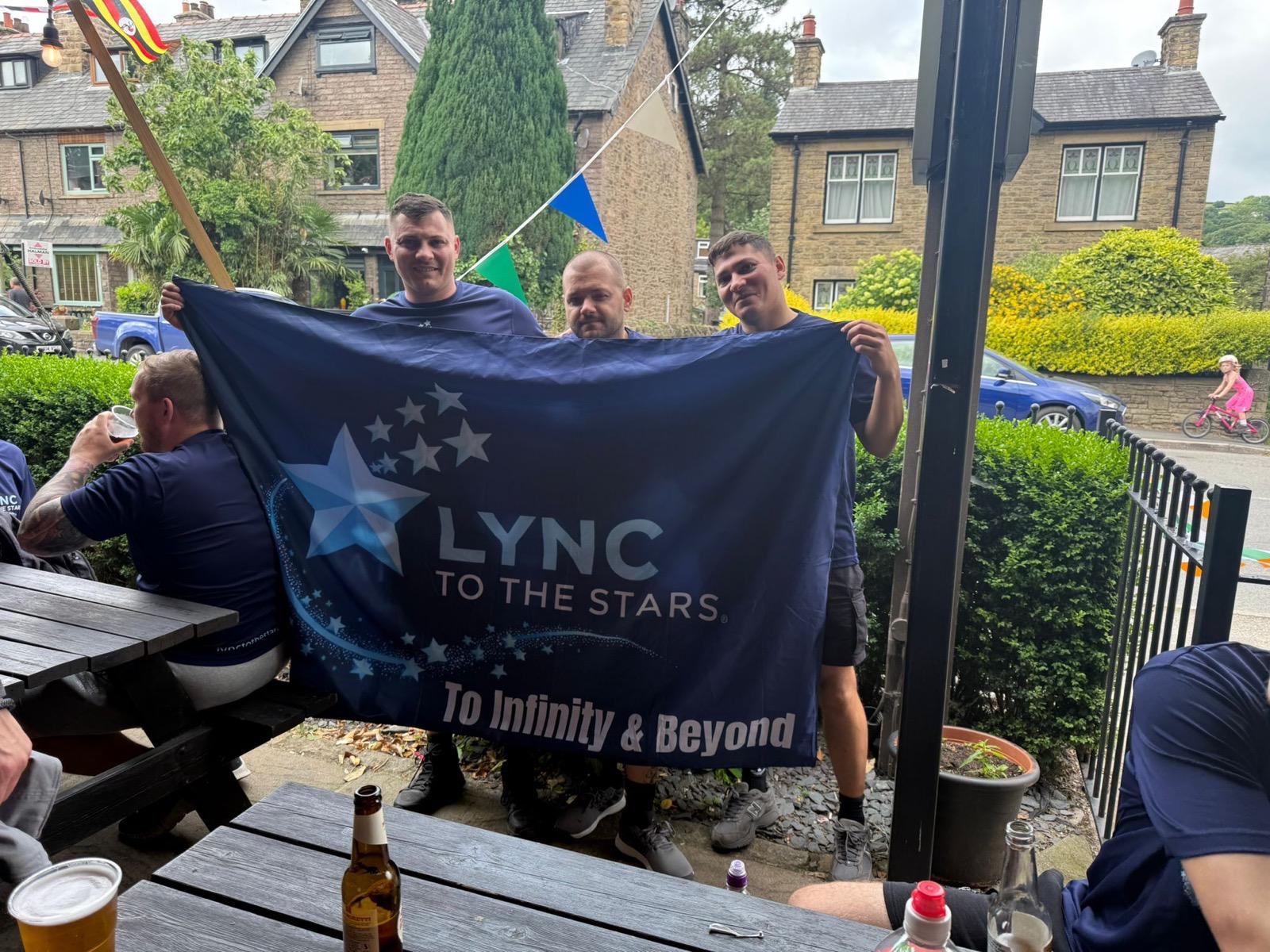 Three of the lads holding the Lync to the Stars banner before setting off