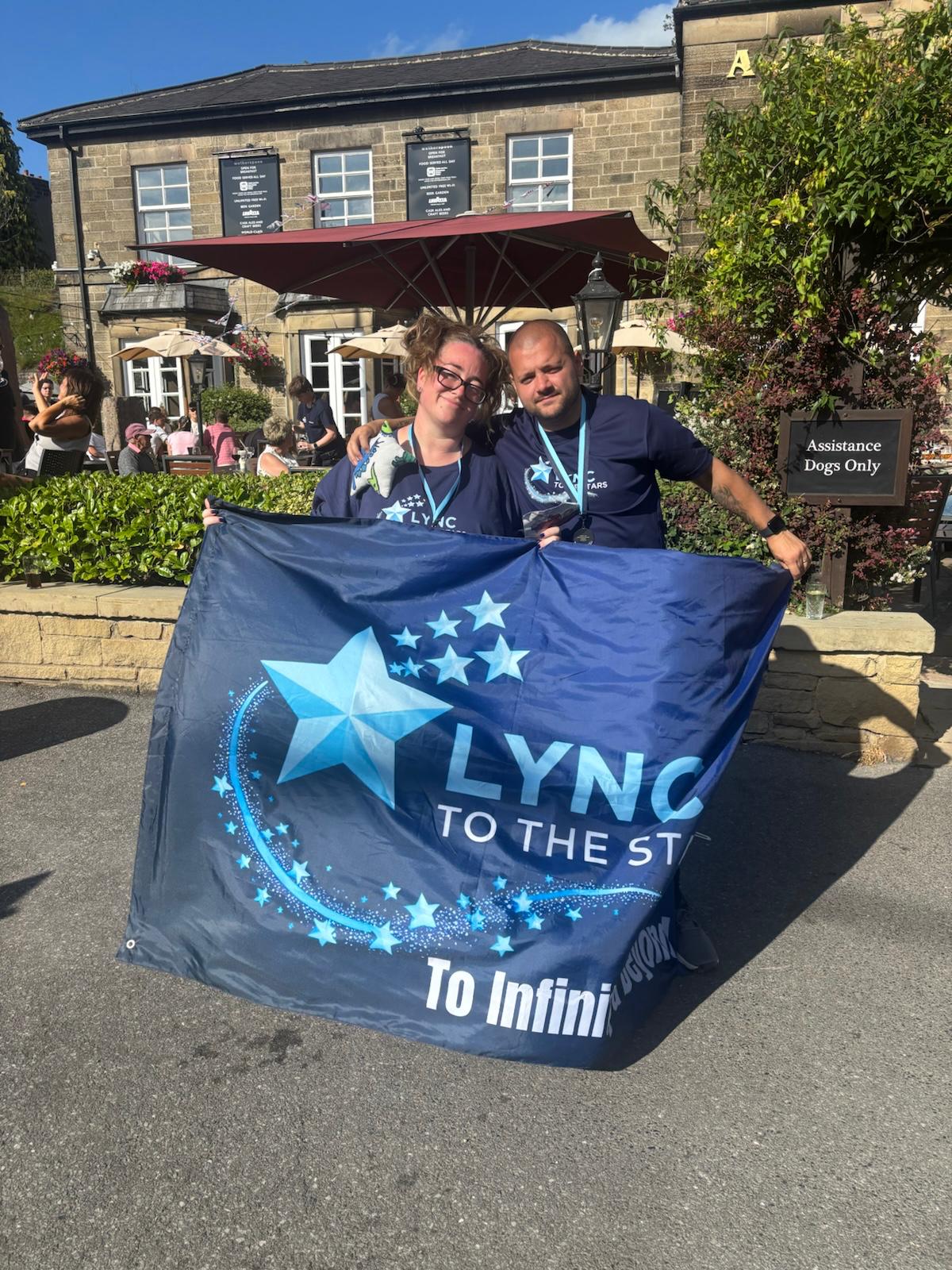 Two walkers with their medals holding the banner at the finish in Buxton