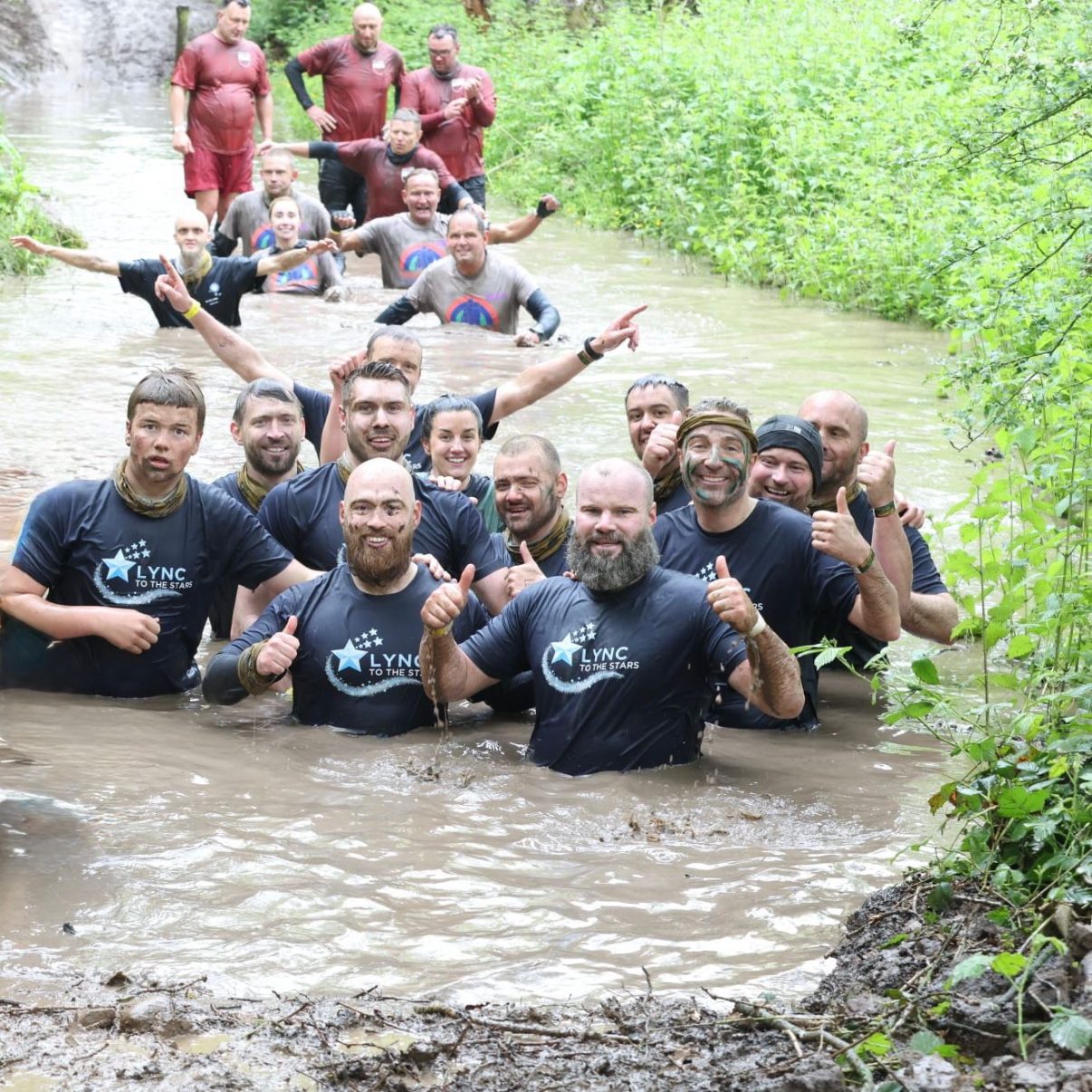 The team waist deep in the muddy water, all smiles