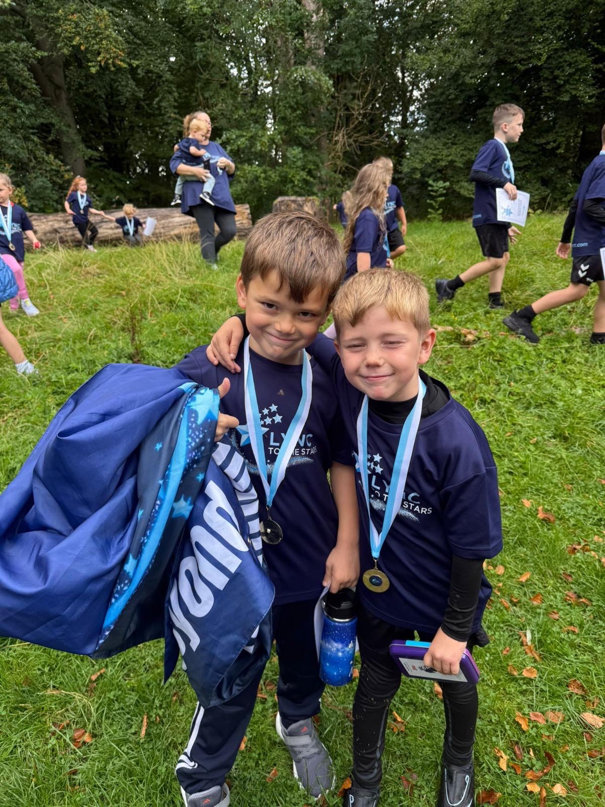 Two boys showing off their medals in their Lync shirts