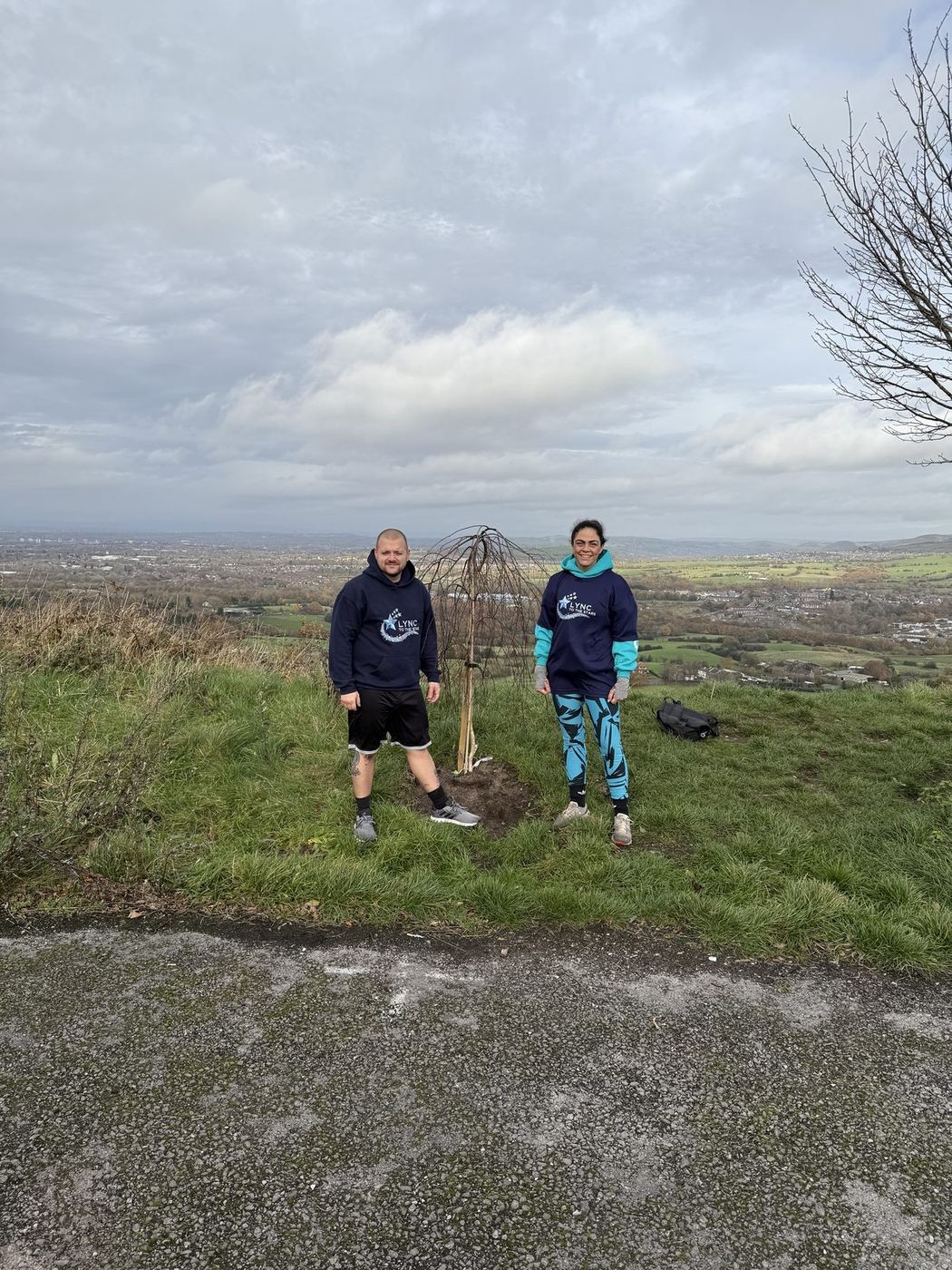 Two visitors standing beside Lync's Tree