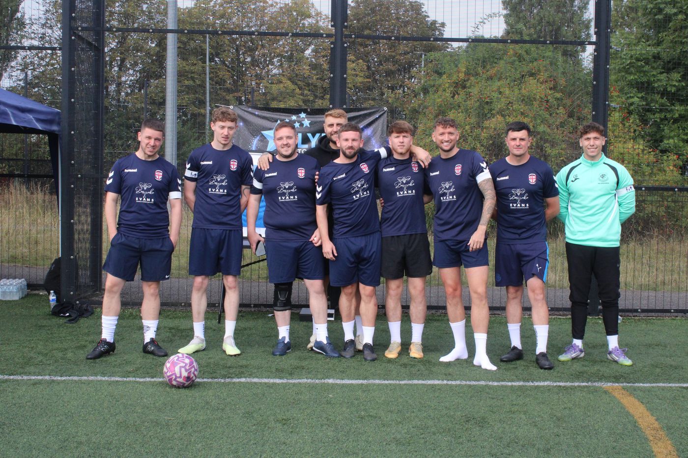 A team in navy kits in front of the Lync to the Stars banner