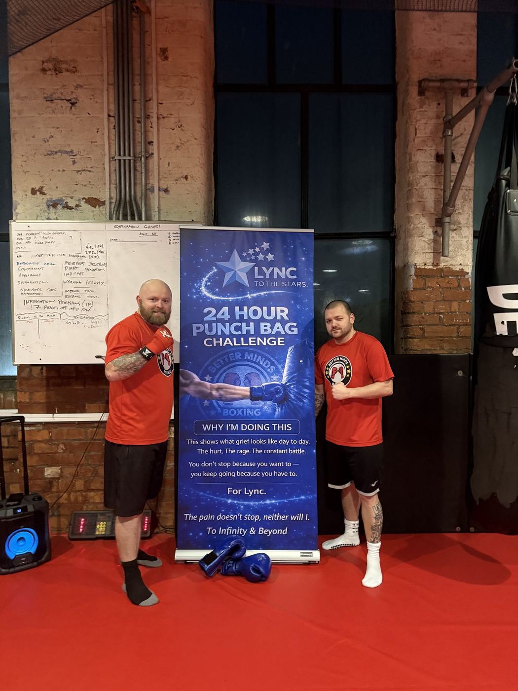 Lee and a friend in boxing gloves beside the challenge banner