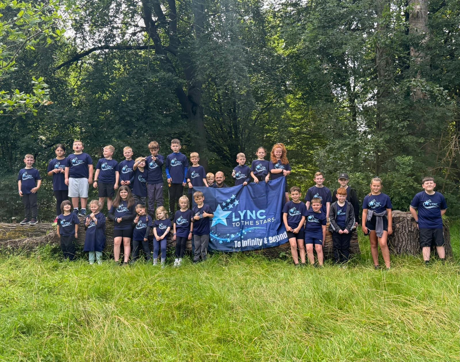 Children holding the Lync to the Stars banner together in the woodland