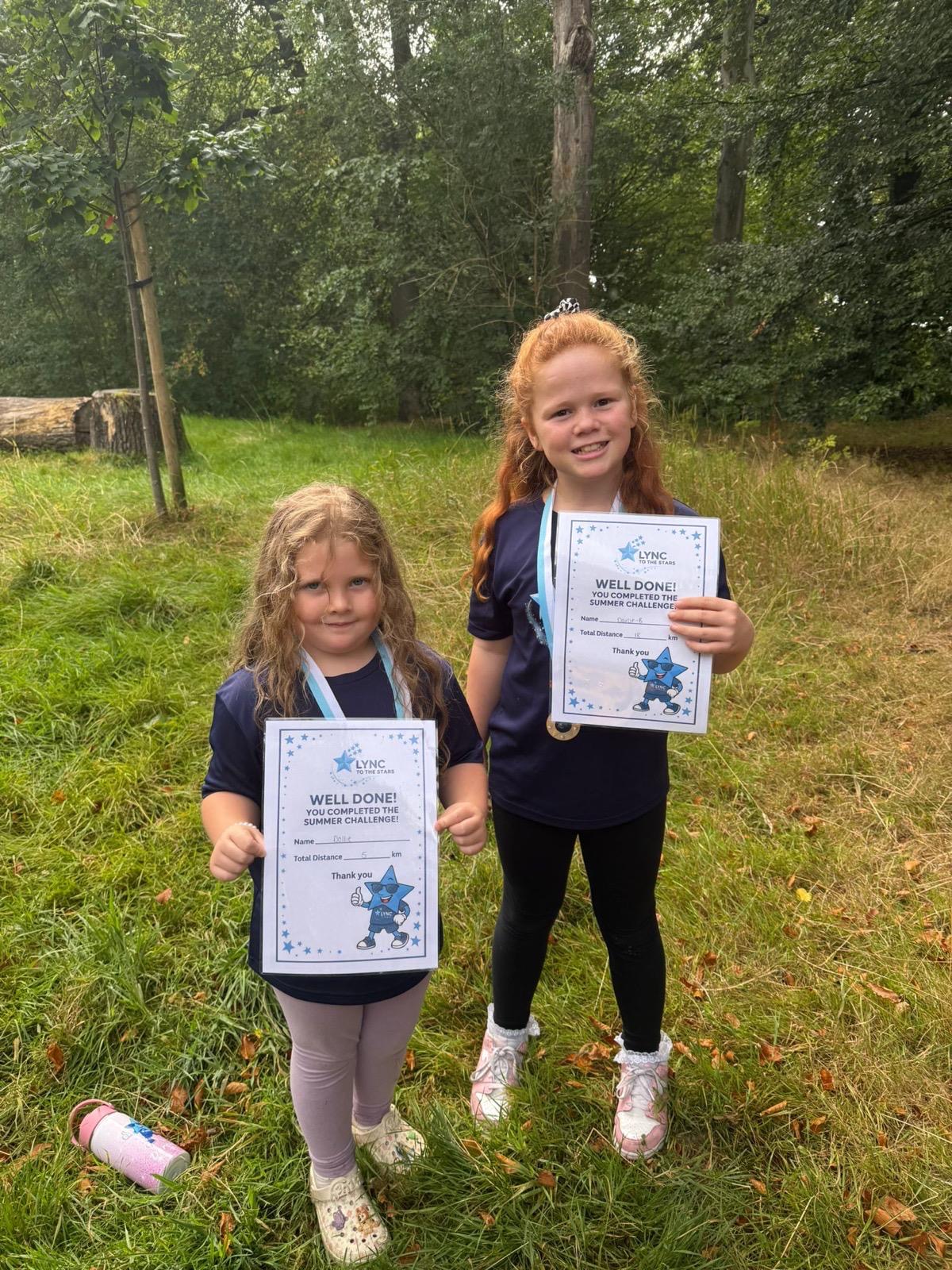 Two girls smiling with their Summer Challenge certificates