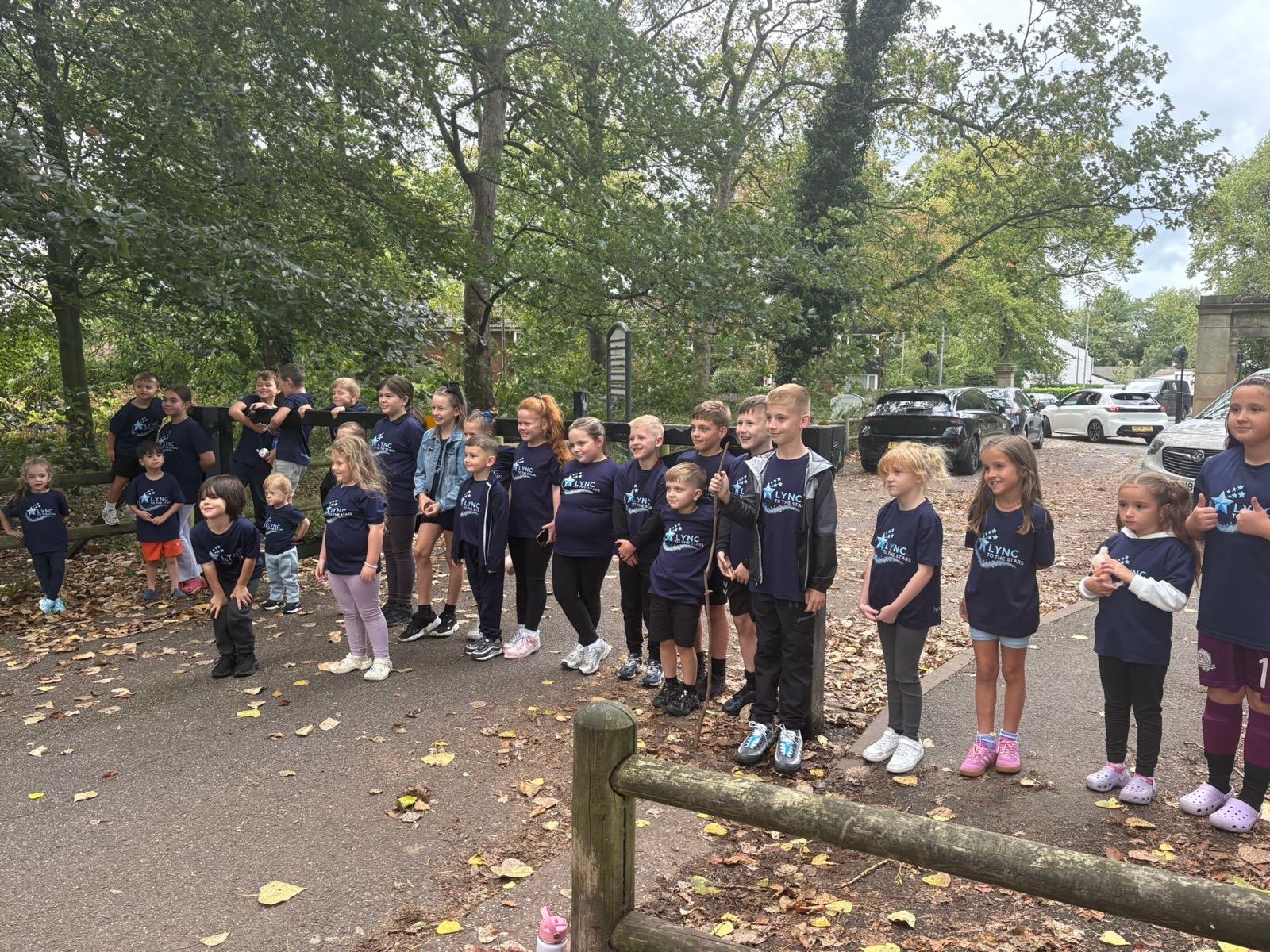 A big group of children in Lync shirts gathered beside the park path