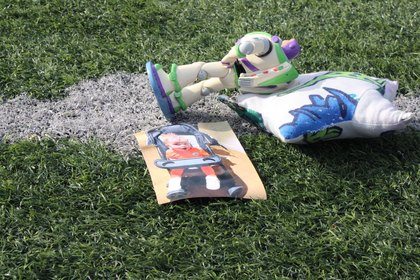 A Buzz Lightyear figure and a photo of Lync laid on the pitch